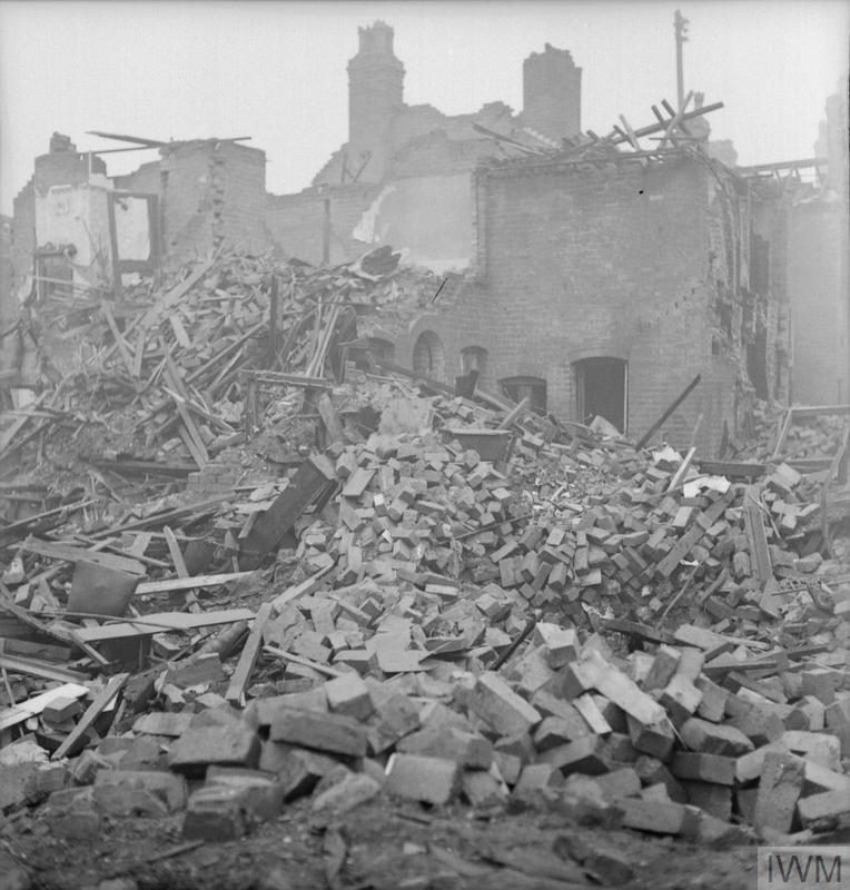 A large pile of brick rubble, timber and other debris is all that remains of this house on James Street in Aston Newtown, Birmingham, following an air raid. The other houses which can be seen in the background have also sustained a huge amount of damage.
