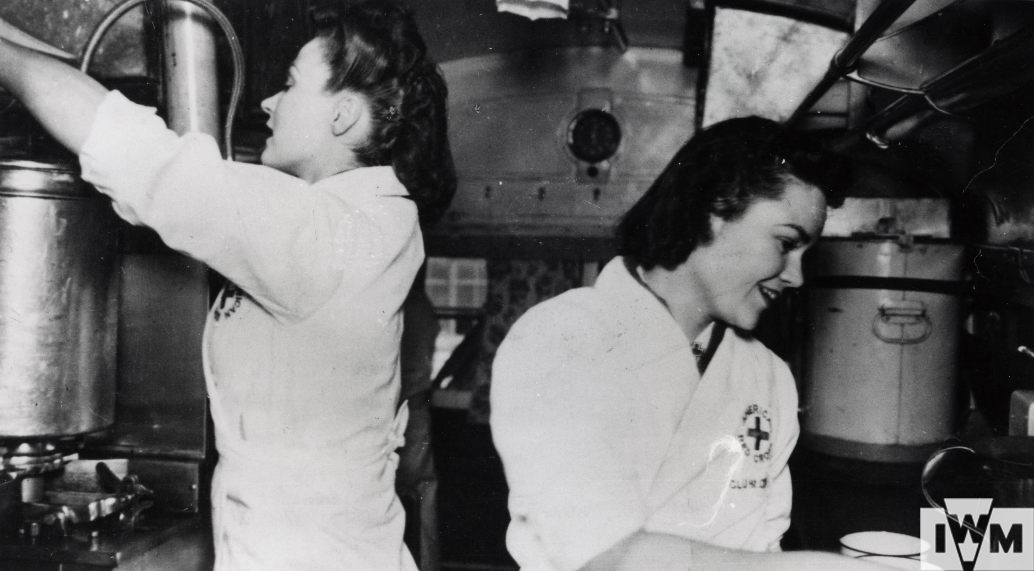 Two American Red Cross nurses in a mobile canteen preparing food and drink for USAAF airmen. caption on image: "American Red Cross Clubmobile "Somewhere" In Great Britain. "American Doughgirls".