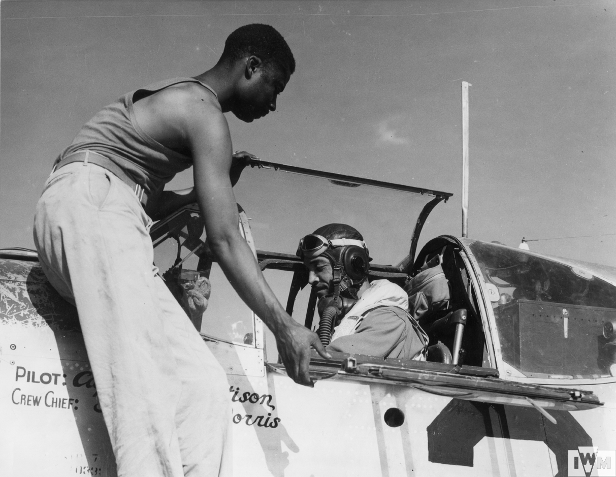 Staff-Sergeant Alfred D Morris, crew chief of the 332nd Fighter Group, 15th Air Force, helps Captain William T Mattison into the cockpit of his P-51 Mustang. 