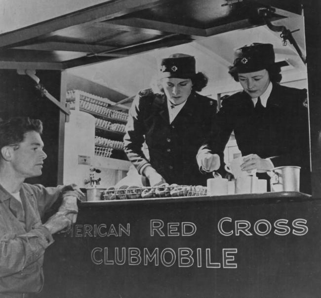 Two Clubmobile volunteers serve coffee and donuts to US ground personnel on an air base in ENgland