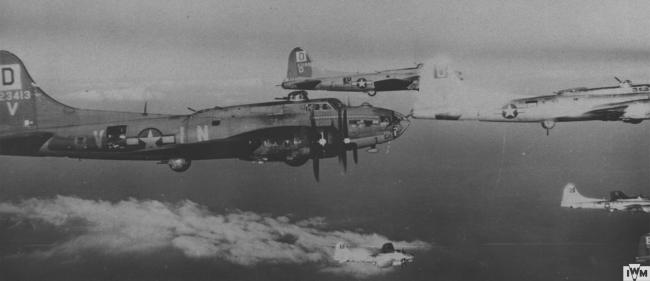 A flight of B-17 Flying Fortresses of the 100th Bomb Group fly in formation. B-17 (serial number 42-3413) nicknamed "Hard Luck" is the foremost aircraft, with B-17 (serial number 42-31991) nicknamed "Miss Chief" flying alongside in the background.